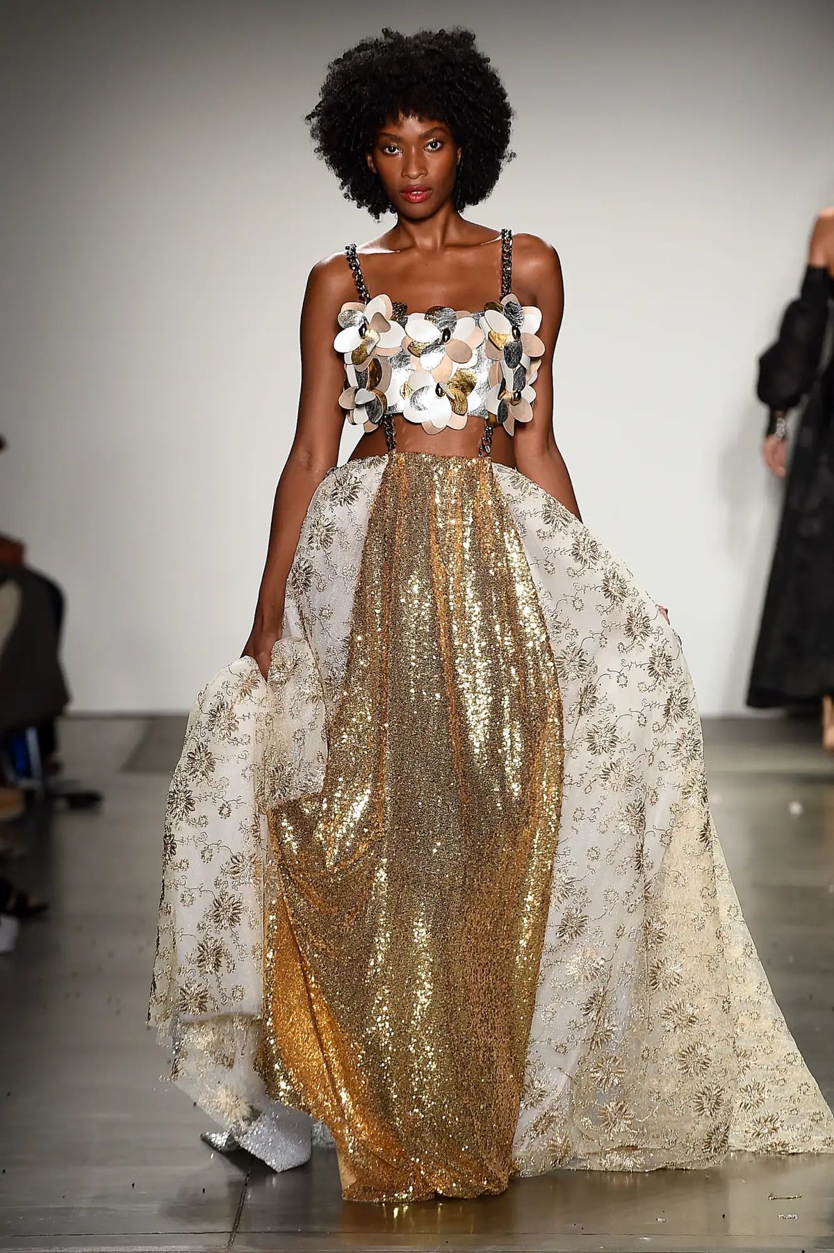 FRAQAIR on the runway: gold sequin skirt under ivory and gold embroidered tulle, with a bustier of leather flowers on chain straps